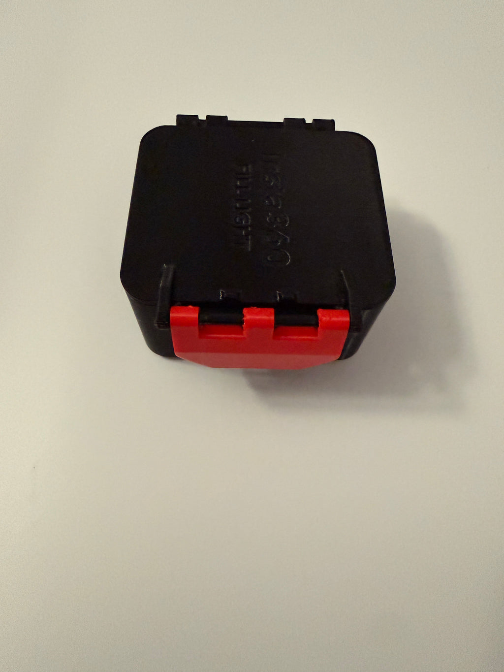 Black 3D printed carrying case with red latch and hinged lid, closed.